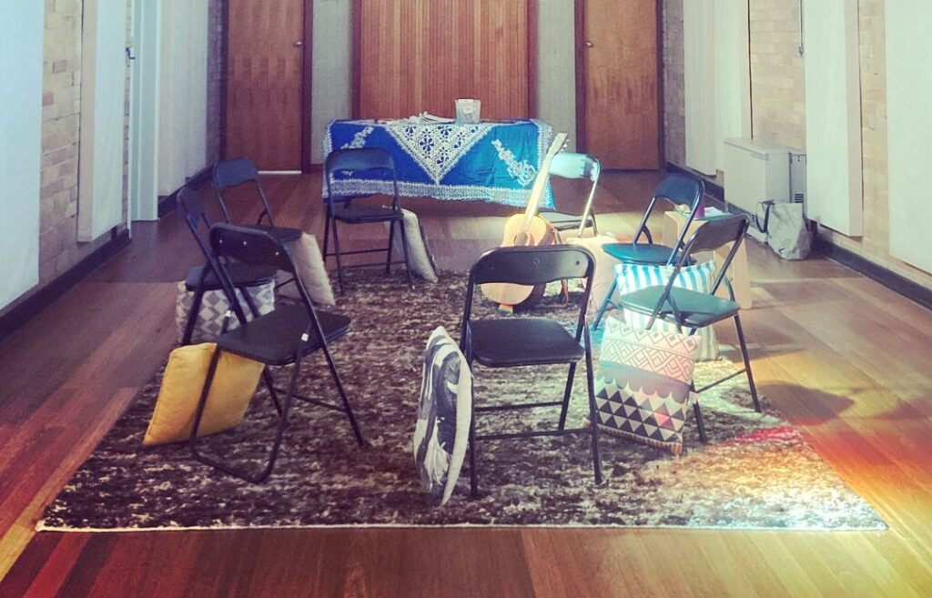 A photo of a room ready for a music therapy group, with cushions, instruments and chairs in a circle