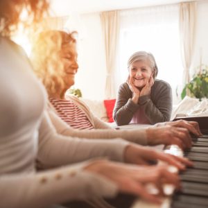 A friend watching an older lady engaging with music therapy for dementia